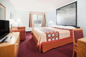 Super 8 by Wyndham Kindersley في Kindersley: غرفة فندق بسرير وتلفزيون