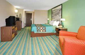 
a hotel room with a bed, chair, desk and television at Super 8 by Wyndham Denver Stapleton in Denver
