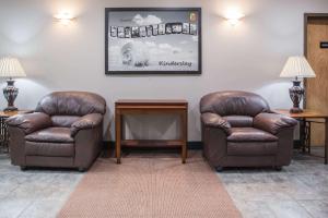 two leather chairs and a table in a waiting room at Super 8 by Wyndham Kindersley in Kindersley