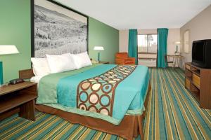 
a hotel room with a bed, chair, table and television at Super 8 by Wyndham Denver Stapleton in Denver
