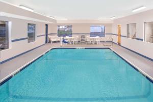 a large swimming pool in a room with a table and chairs at Super 8 by Wyndham Three Rivers in Three Rivers
