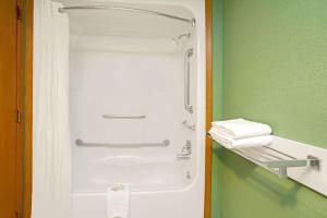a shower in a green bathroom with towels on a shelf at Super 8 by Wyndham Denver Stapleton in Denver