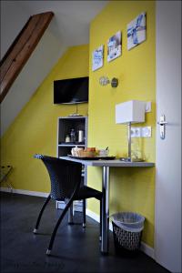 een eetkamer met een tafel en een gele muur bij La Croix Verte - Le Relais des Moulins in Bain-de-Bretagne
