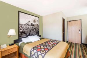 a hotel room with a bed and a painting on the wall at Super 8 by Wyndham Chanute in Chanute