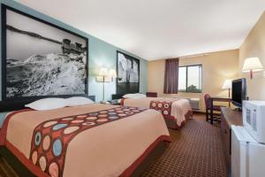 a hotel room with two beds and a flat screen tv at Super 8 by Wyndham Wakeeney in WaKeeney