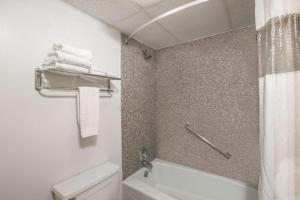 a bathroom with a toilet and a shower with towels at Travelodge by Wyndham Great Bend in Great Bend