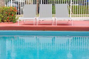 dos sillas blancas sentadas junto a una piscina en Travelodge by Wyndham Fort Lauderdale, en Fort Lauderdale