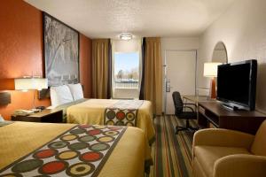 a hotel room with two beds and a flat screen tv at Super 8 by Wyndham Woodward in Woodward