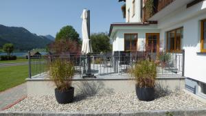 two potted plants in front of a building with an umbrella at Pension Haus Edelweiss in Weissensee