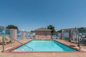ein Pool in einem Resort mit Stühlen um ihn herum in der Unterkunft Super 8 by Wyndham Fort Worth North/Meacham Blvd in Fort Worth