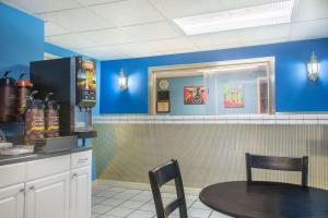 une salle à manger avec une table et un mur bleu dans l'établissement Super 8 by Wyndham Durham/University Area NC, à Durham