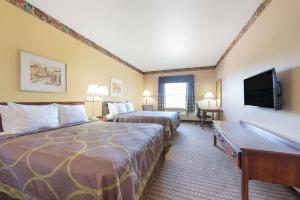 a hotel room with two beds and a flat screen tv at Super 8 by Wyndham Fort Worth North/Meacham Blvd in Fort Worth