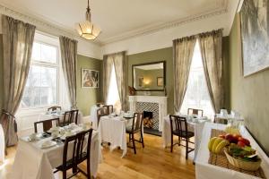 a dining room with white tables and chairs and a fireplace at Greenland house in Castletown