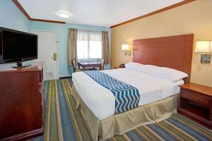 a hotel room with a large bed and a flat screen tv at Travelodge by Wyndham Bishop in Bishop +14 photos