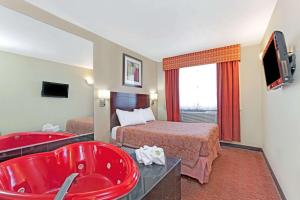 um quarto de hotel com uma banheira vermelha e uma cama em Super 8 by Wyndham Long Island City LGA Hotel em Queens