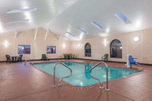 a swimming pool in a large room with tables and chairs at Super 8 by Wyndham St Charles in St. Charles