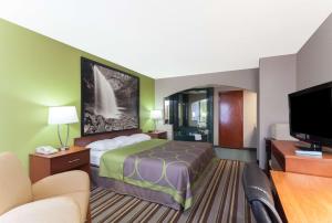 a hotel room with a bed and a flat screen tv at Super 8 by Wyndham Clarksville Northeast in Clarksville