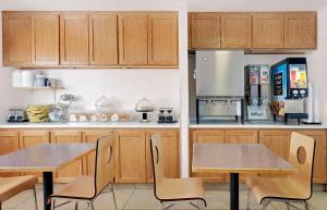 uma cozinha com armários de madeira, 2 mesas e um frigorífico em Travelodge by Wyndham Page, View of Lake Powell em Page