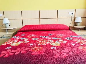een bed met een rode sprei met bloemen erop bij Apartamentos Boutique Valparaiso in Oropesa del Mar