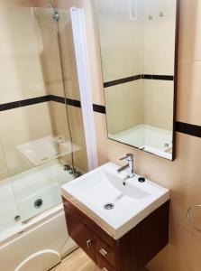 een badkamer met een wastafel, een spiegel en een bad bij Apartamentos Boutique Valparaiso in Oropesa del Mar