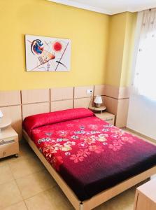 sypialnia z łóżkiem z czerwoną kołdrą w obiekcie Apartamentos Boutique Valparaiso w mieście Oropesa del Mar