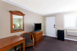 um quarto com uma televisão e uma secretária com uma cadeira em Super 8 by Wyndham Torrance LAX Airport Area em Torrance