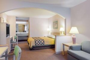 a hotel room with a bed and a living room at Super 8 by Wyndham Jasper TX in Jasper