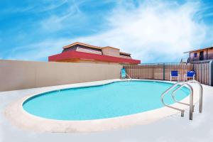 a swimming pool with two chairs and a building at Travelodge by Wyndham Barstow in Barstow
