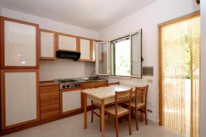 cocina con mesa, sillas y ventana en Residence Delfino en Vieste