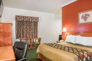 a small hotel room with a bed and a chair at Super 8 by Wyndham Brookshire TX in Brookshire