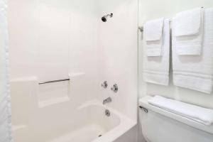 a white bathroom with a shower and a toilet and towels at Post Oak Inn in Brownwood