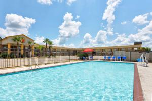 a pool at a resort with chairs and a building at Super 8 by Wyndham Breaux Bridge in Breaux Bridge
