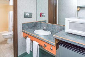 y baño con lavabo, aseo y microondas. en Travelodge by Wyndham Kalispell, en Kalispell