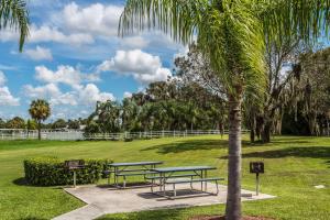 a park with two picnic tables and a palm tree at Travelodge Suites by Wyndham Lake Okeechobee in Okeechobee