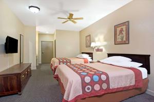 a hotel room with two beds and a ceiling fan at Super 8 by Wyndham St. Louis Airport in Woodson Terrace