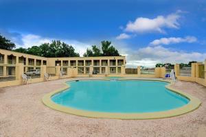 uma grande piscina com cadeiras e um edifício em White Rock Inn em San Marcos