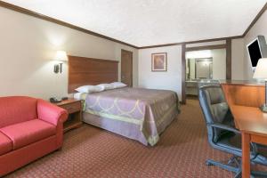 a hotel room with a bed and a desk and a chair at Super 8 by Wyndham Enid in Enid