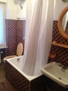 a bath tub with a shower curtain next to a sink at Alloggio a Sestriere fronte piste in Sestriere