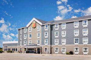 un gran edificio gris con un cartel. en Super 8 by Wyndham Kapuskasing, en Kapuskasing