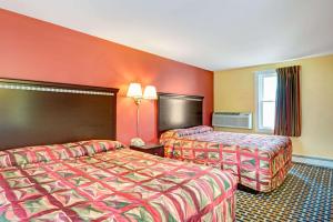 two beds in a hotel room with orange walls at Budget Inn in South Portland