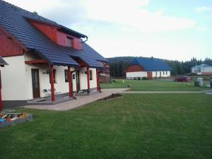 a red and white building with a grass yard at Apartmán u Hovorků in Borová Lada