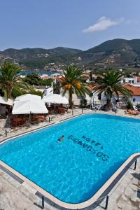 uma grande piscina com palmeiras e guarda-sóis em Dionyssos em Skopelos