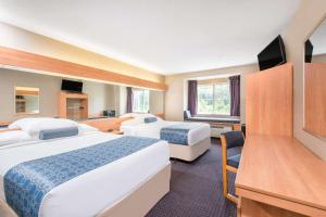 a hotel room with two beds and a flat screen tv at Microtel Inn & Suites by Wyndham Hazelton/Bruceton Mills in Hazelton
