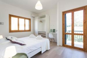 a white bedroom with a bed and a window at BOBO' in Marina di Ragusa