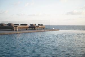 een zwembad met banken en stoelen naast het water bij Almyra in Paphos City
