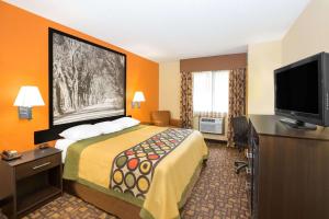 a hotel room with a bed and a flat screen tv at Super 8 by Wyndham Clive IA in Clive