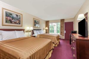 a hotel room with two beds and a flat screen tv at Travelodge by Wyndham Seymour in Seymour