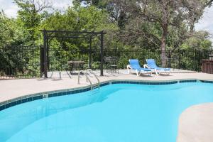 a swimming pool with two blue chairs and a table at Microtel Inn by Wyndham Stillwater in Stillwater