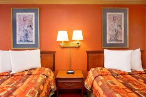 2 camas en una habitación de hotel con paredes de color naranja en Knights Inn Port Charlotte, en Port Charlotte