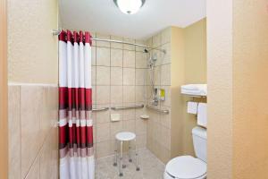 a bathroom with a shower with a red and white shower curtain at Knights Inn Port Charlotte in Port Charlotte +6 photos